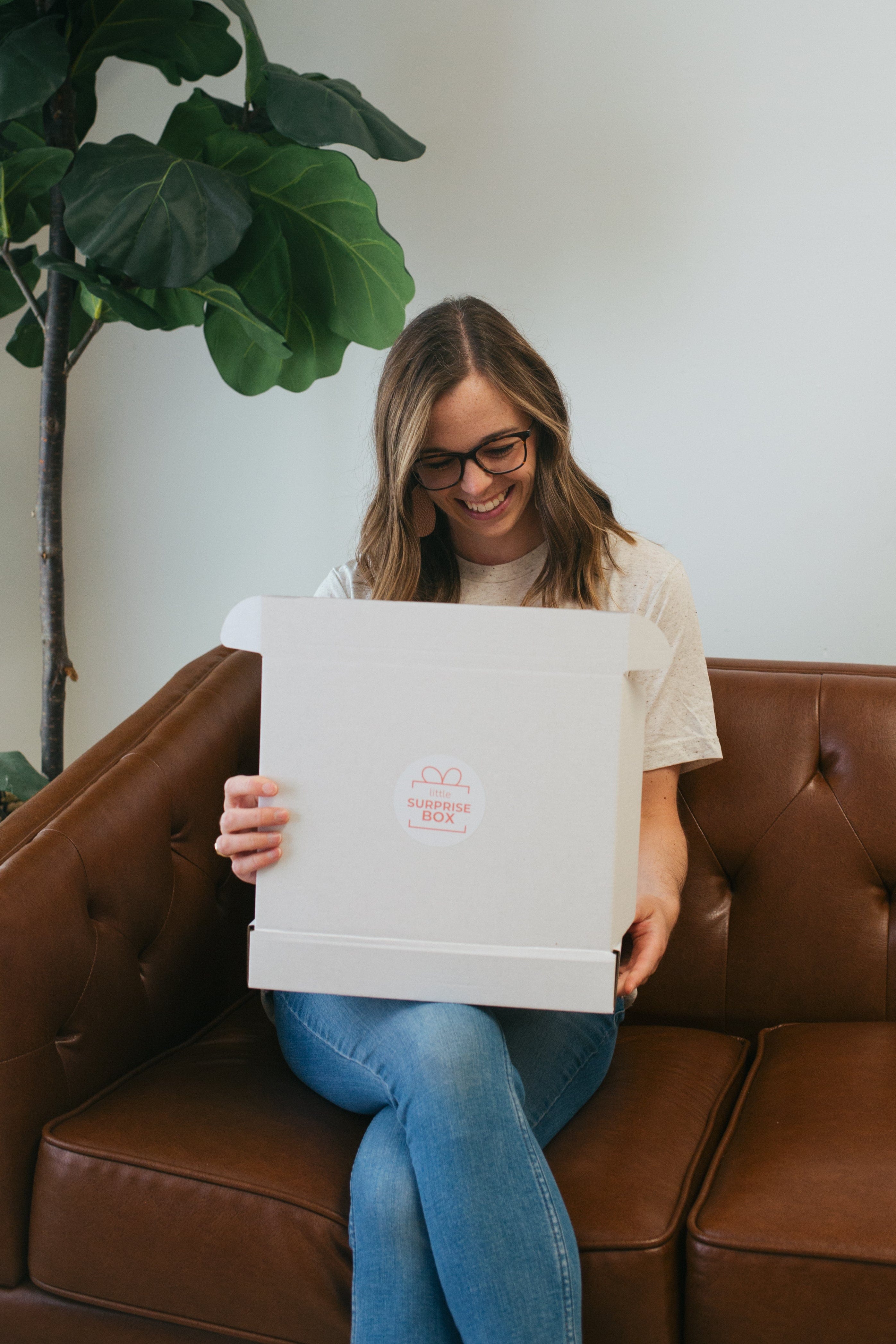 Woman on couch holding open box.