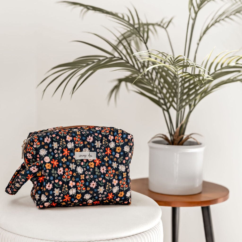 Floral patterned bag on a stool next to a potted plant.