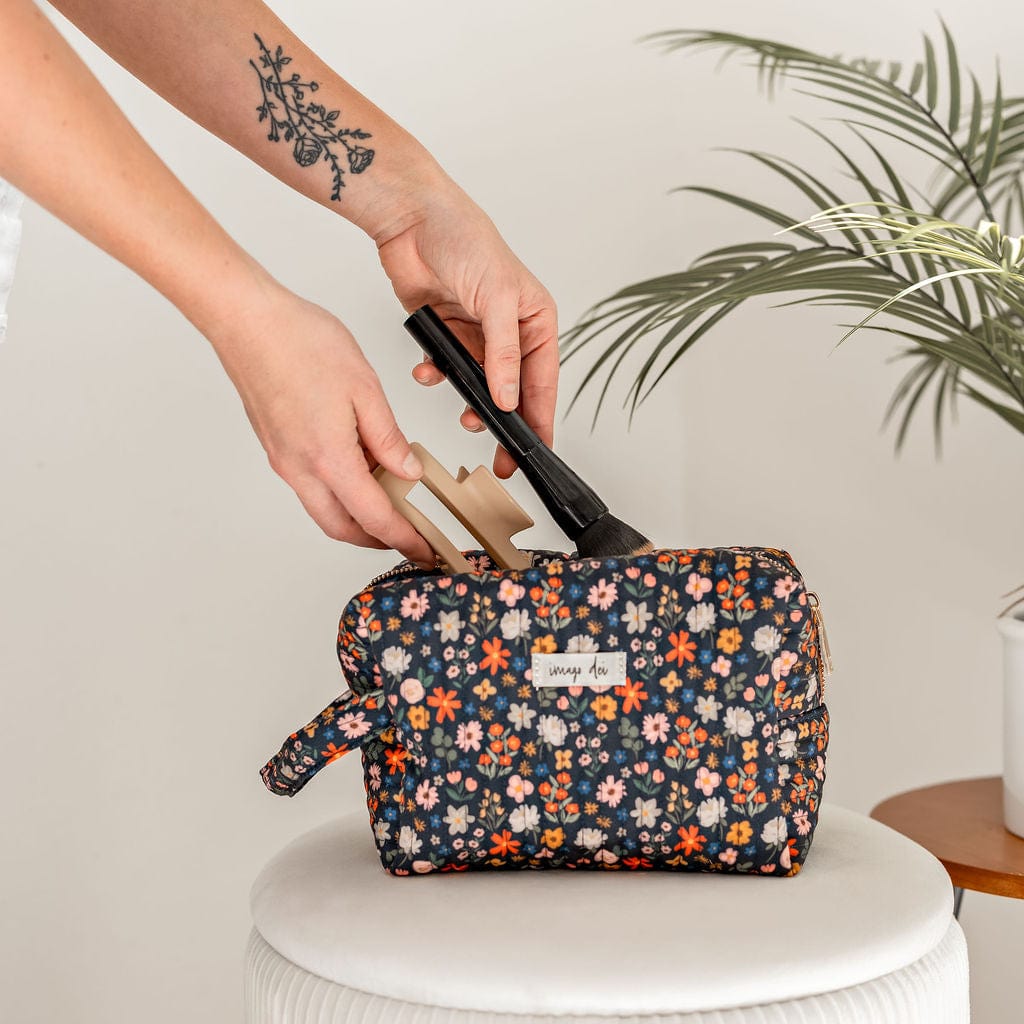 Person putting items into a floral makeup bag.