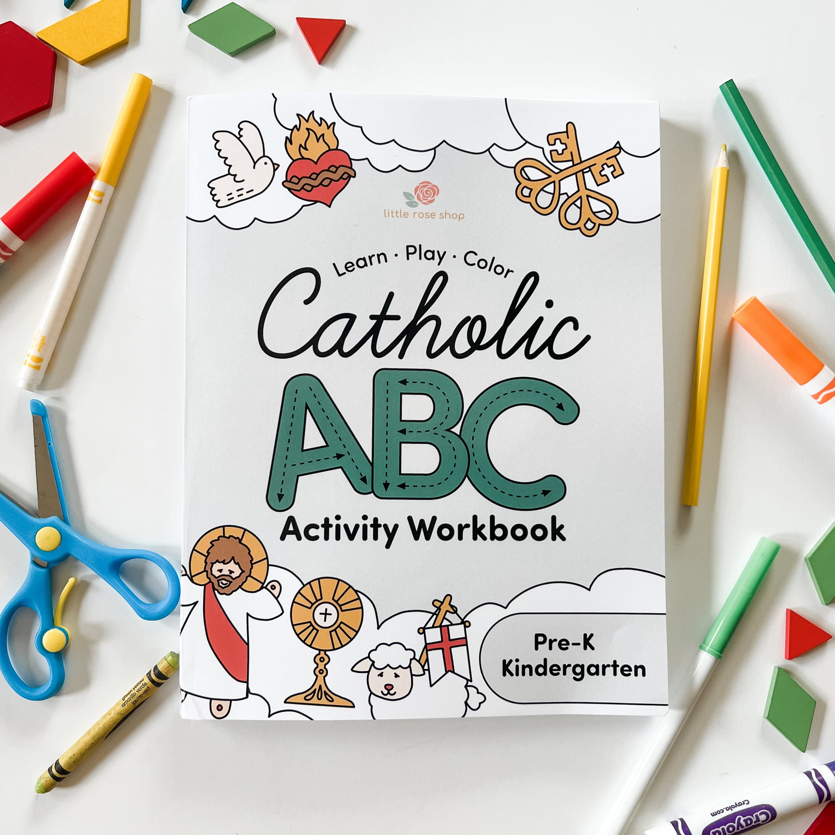 Catholic ABC Activity Workbook flatlay with colorful school supplies.
