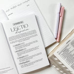 Open book with guide, notepad, pens, and bible pages.
