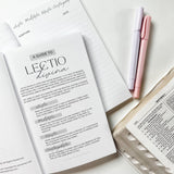 Open book with guide, notepad, pens, and bible pages.