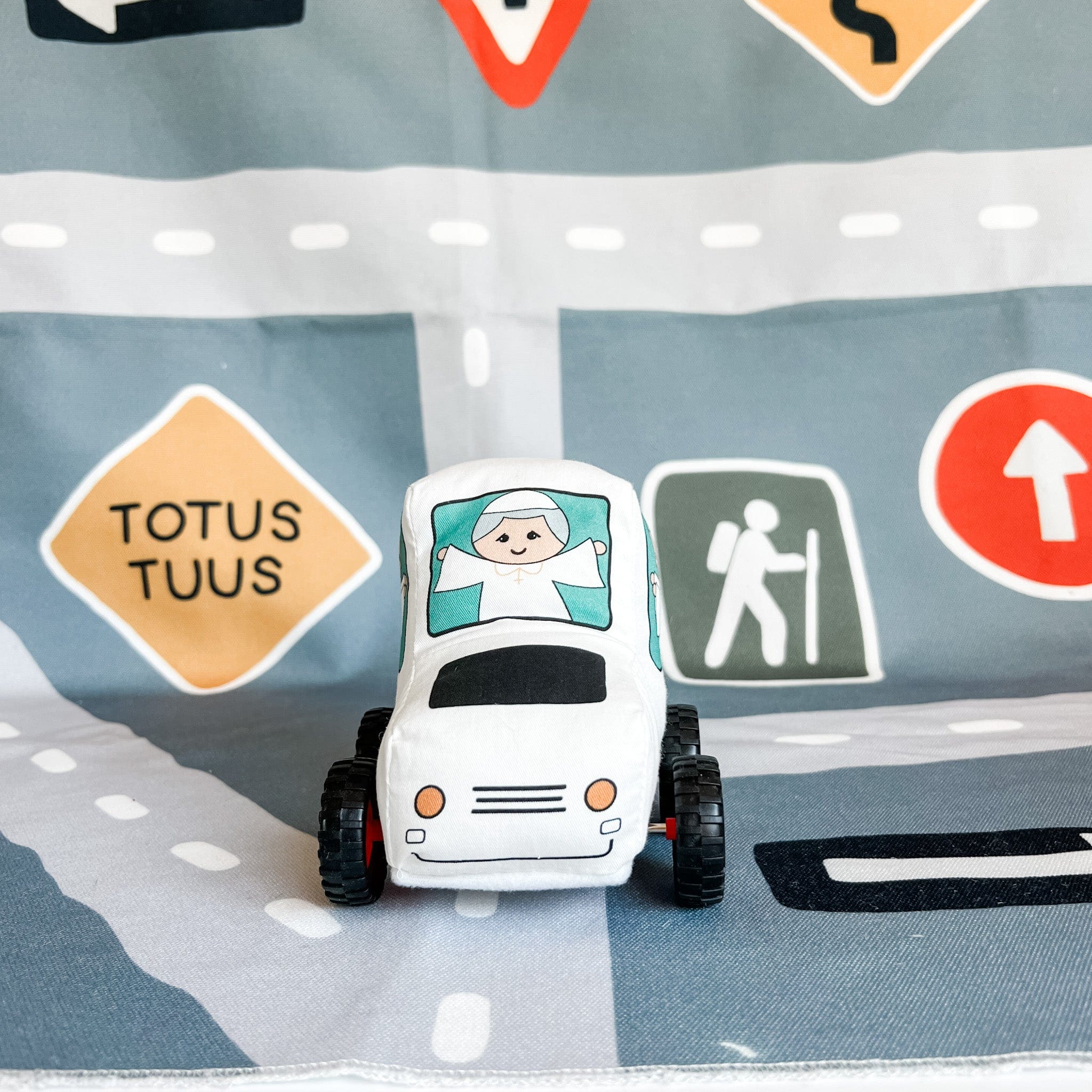 Toy car on a road mat with road signs.