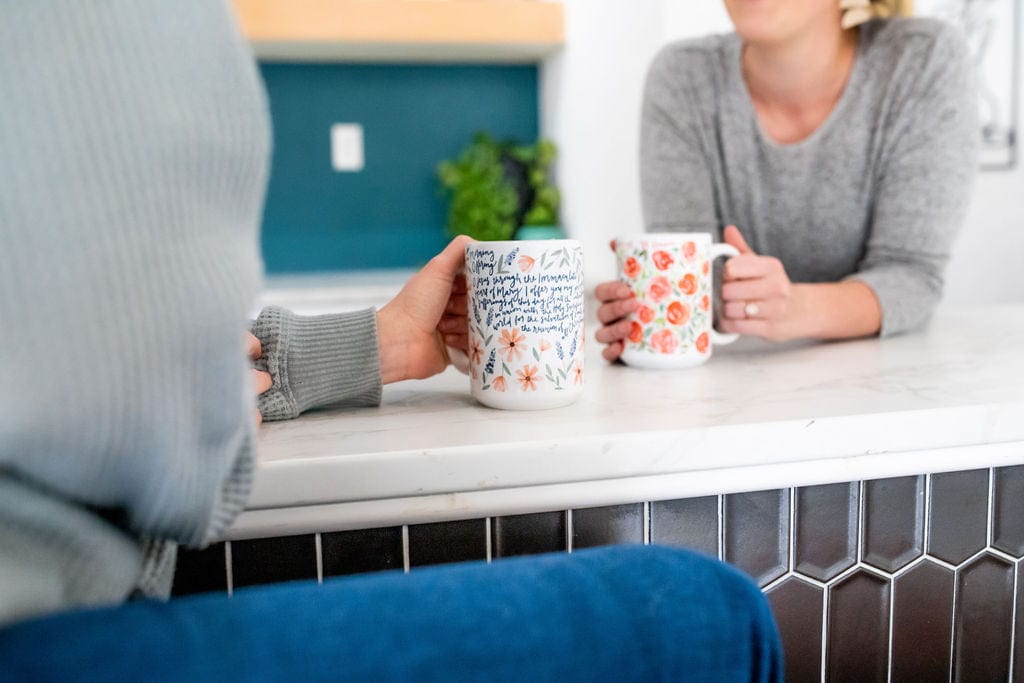 Two people holding mugs at a counter.