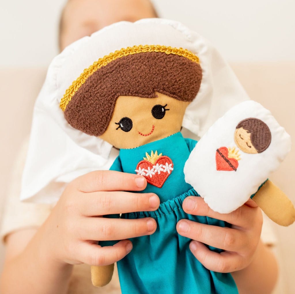 Child holding Mary and baby Jesus dolls.