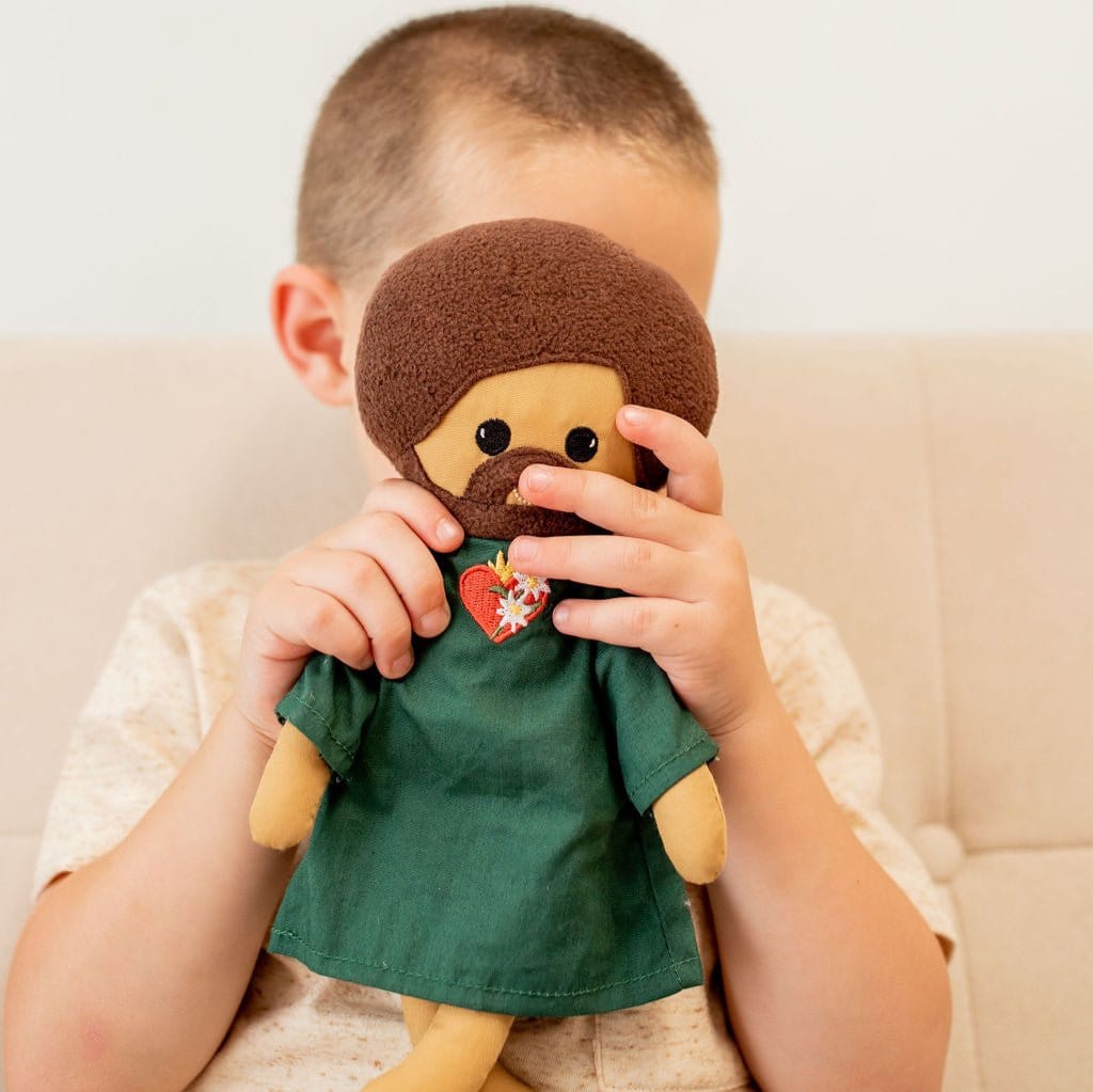 Boy holding a doll with brown hair and a green shirt.