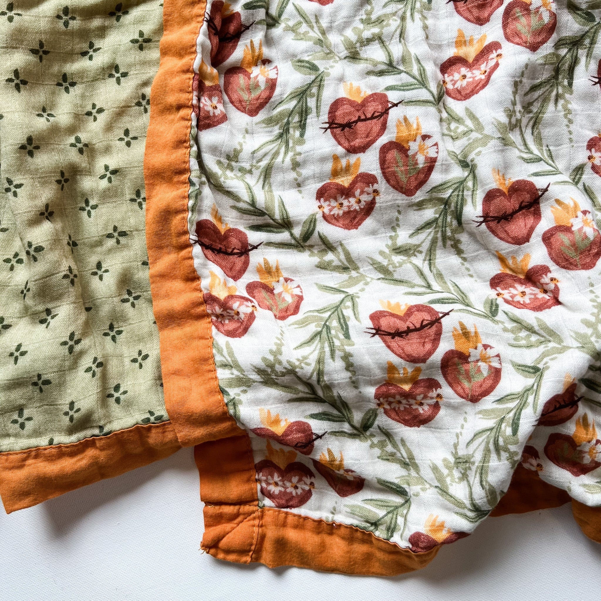 Quilt with floral and heart pattern, orange trim.