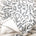 White blanket with black floral design and script.