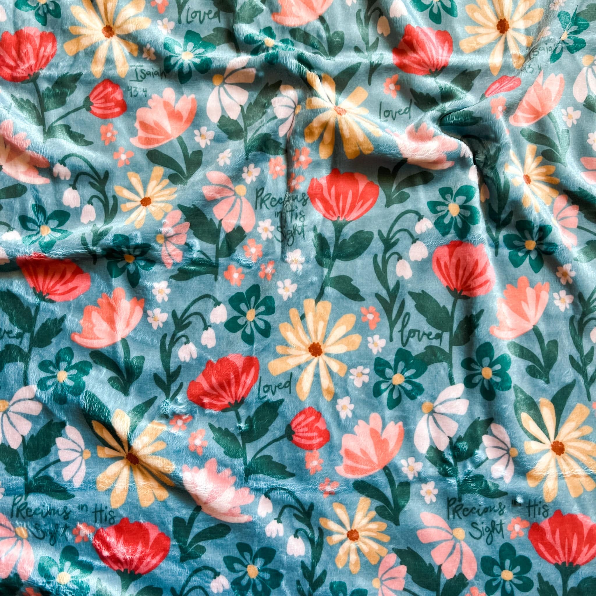 Floral blanket with red, yellow, and white flowers on teal.