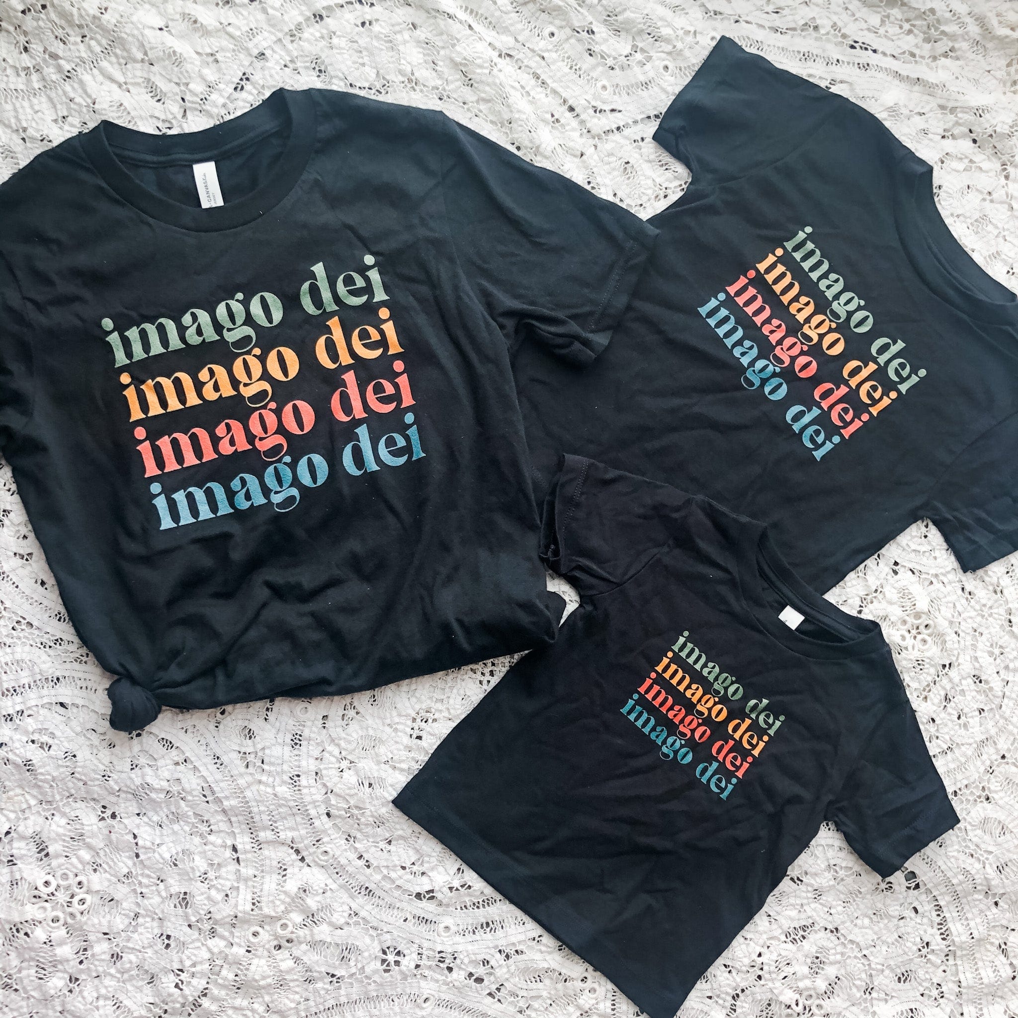 Three black t-shirts with imago dei in colorful text.
