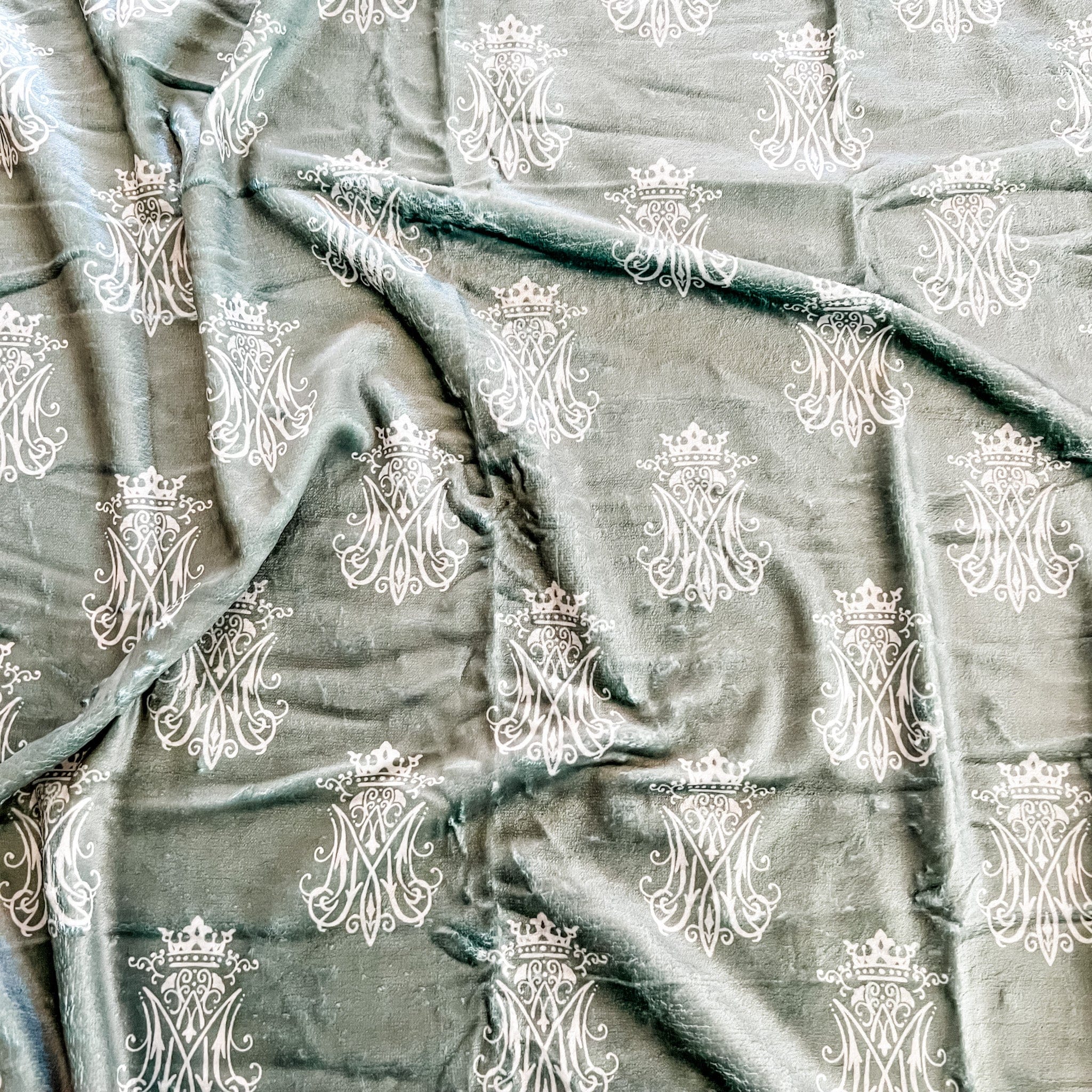 Teal fabric with repeating white emblem pattern.