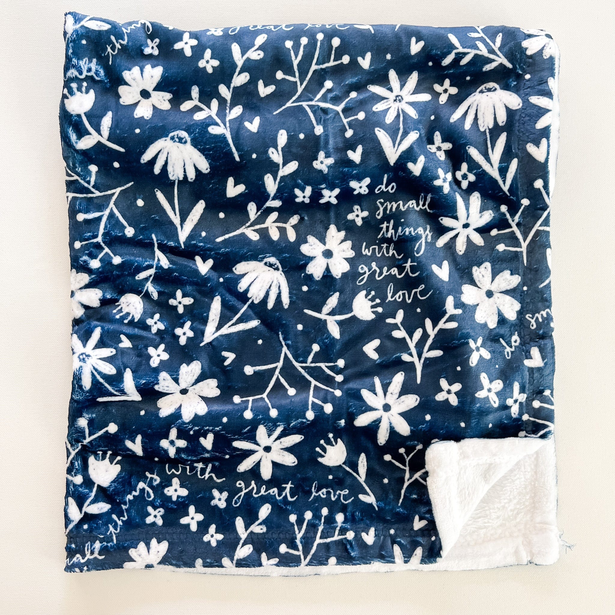 Navy blanket with white floral pattern and text.