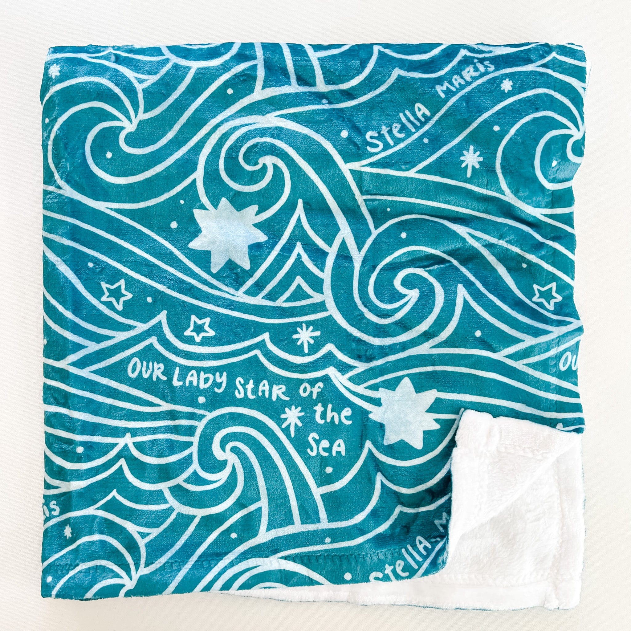 Teal blanket with white wave and star pattern.
