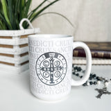 White coffee mug with Saint Benedict medal design.