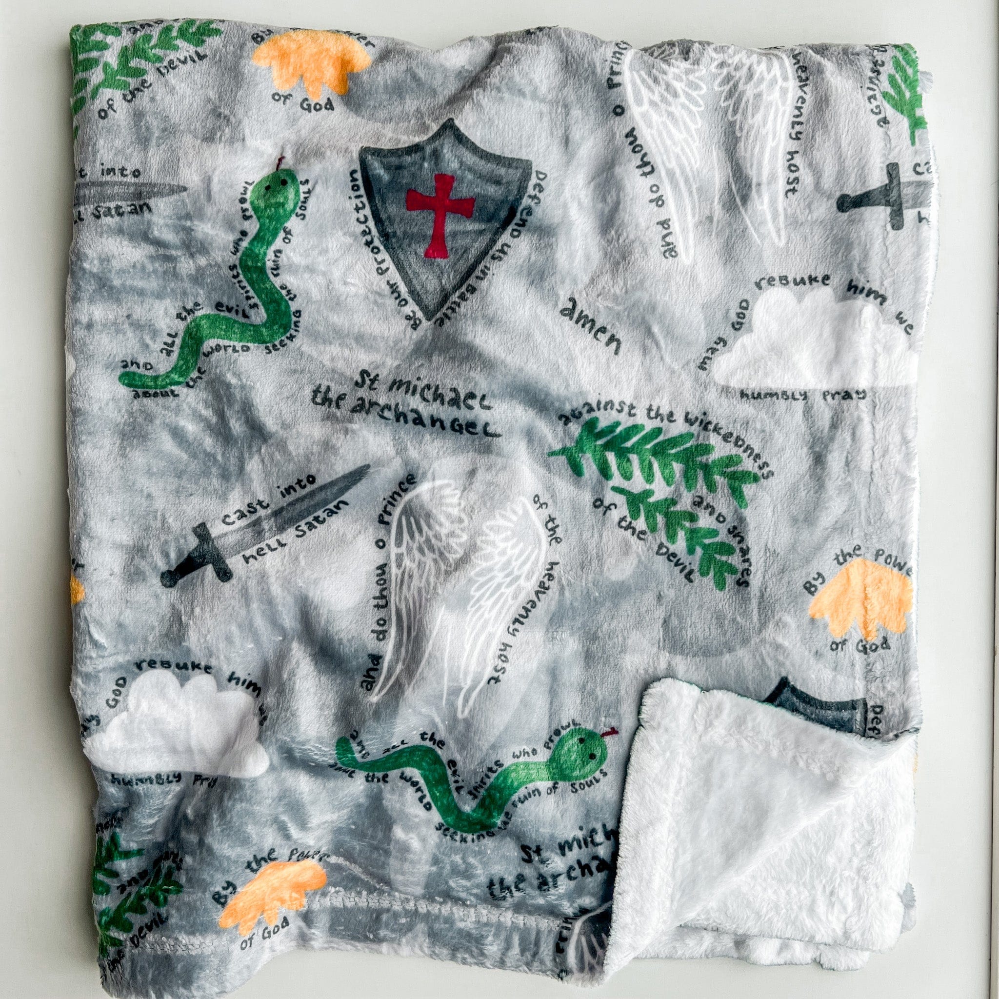 Gray blanket with religious imagery and text.