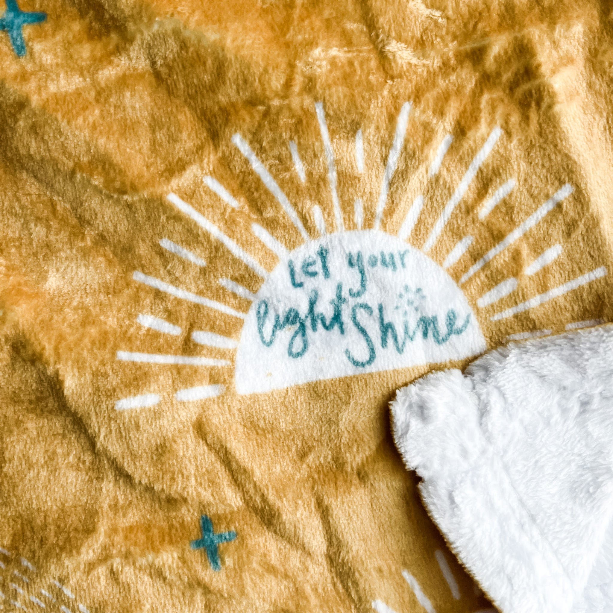Mustard yellow blanket with sun design and text.