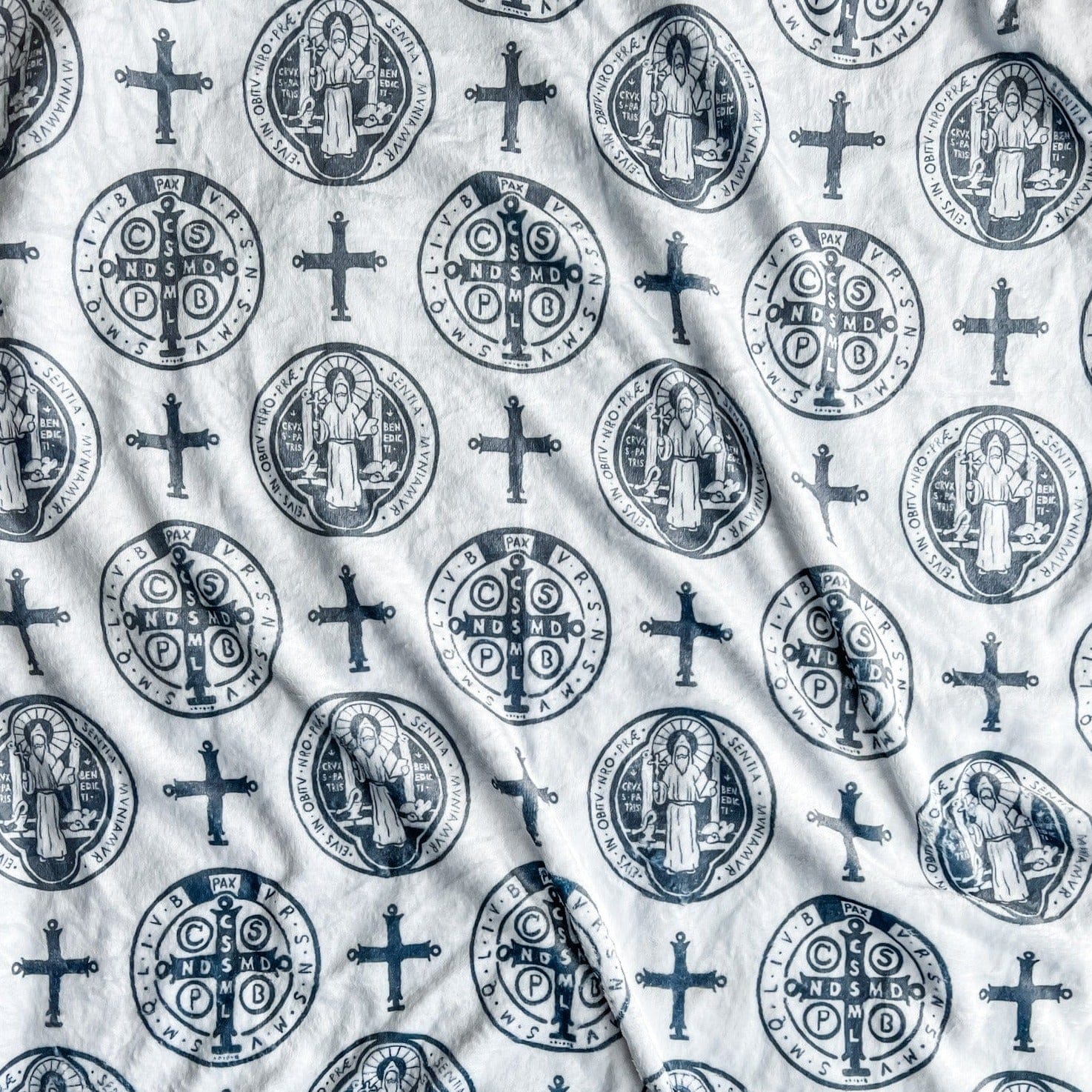 White fabric with repeating religious symbols.