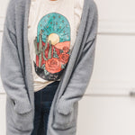 Woman in gray cardigan with desert scene t-shirt.
