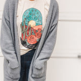 Woman in gray cardigan with desert scene t-shirt.