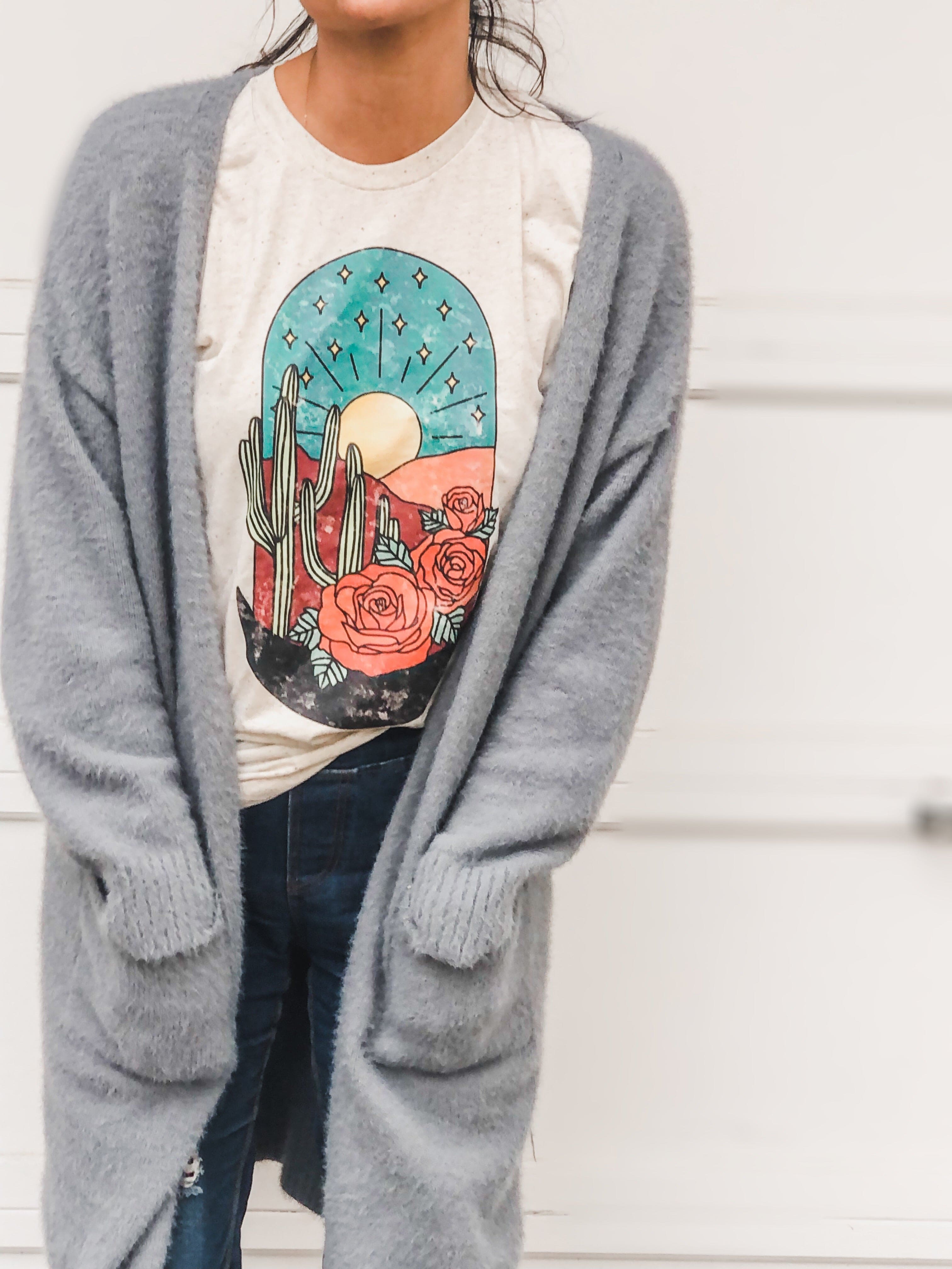 Woman in gray cardigan with desert scene t-shirt.