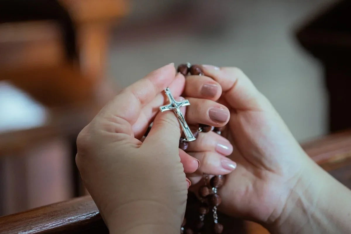 woman showing the blessed Rosary meaning by praying with her blessed Rosary in Church