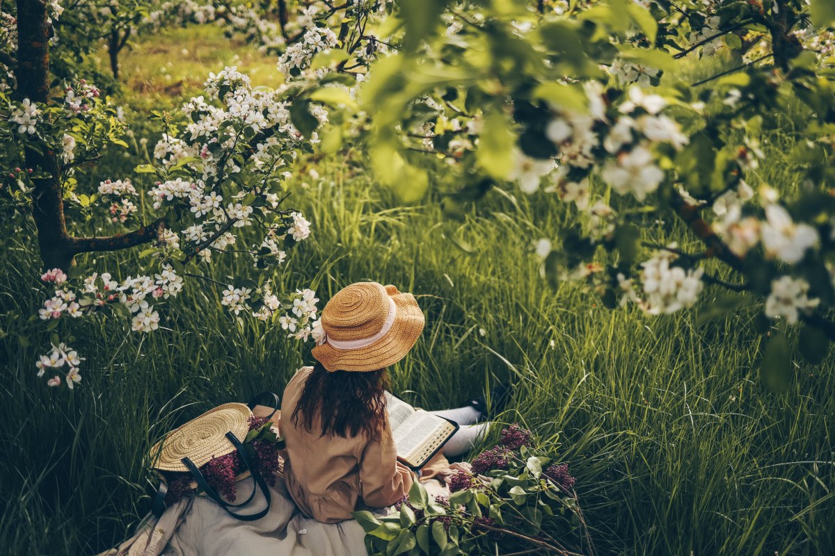 Confirmation gift ideas for girl sitting in garden surrounded by flowers.