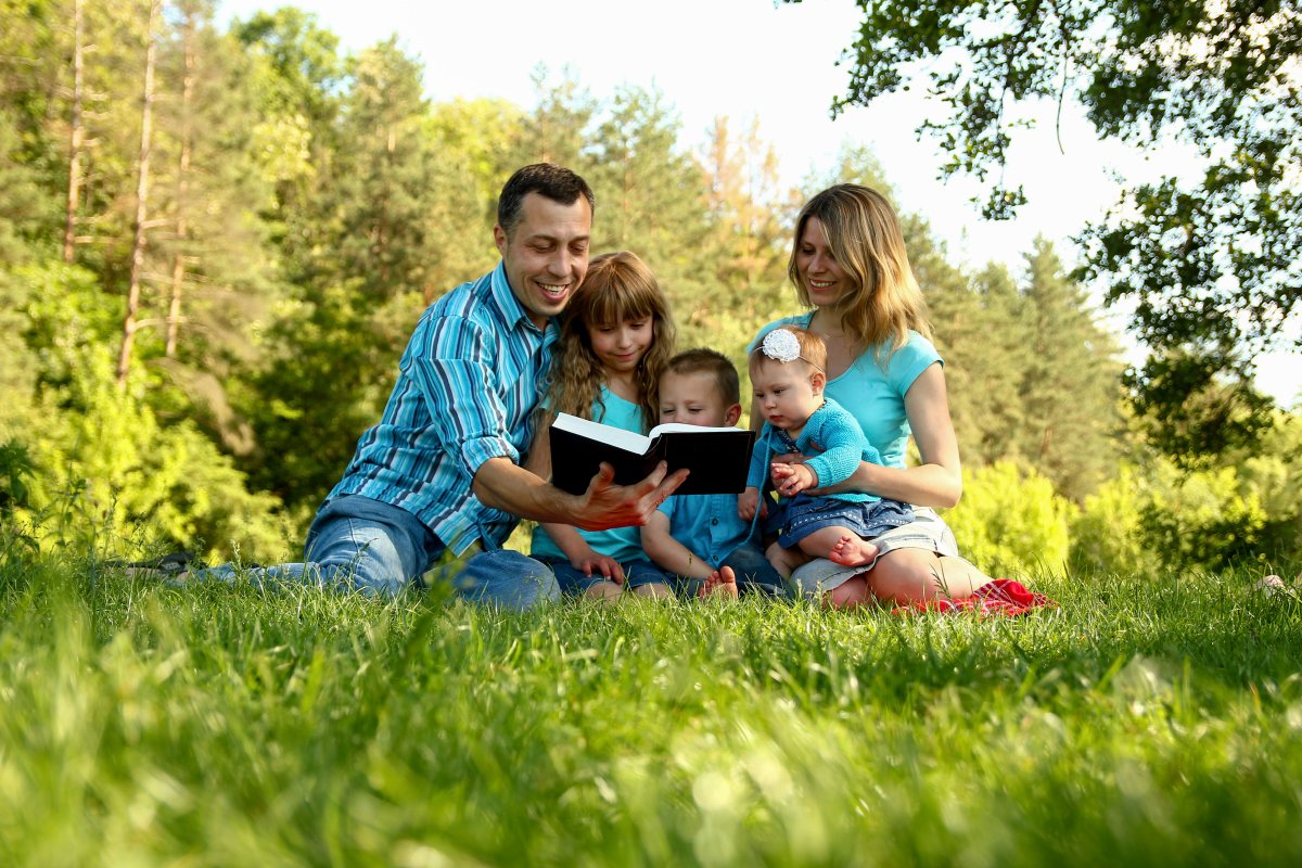Family reading the bible on the lawn while thinking of the best gifts for Christians.