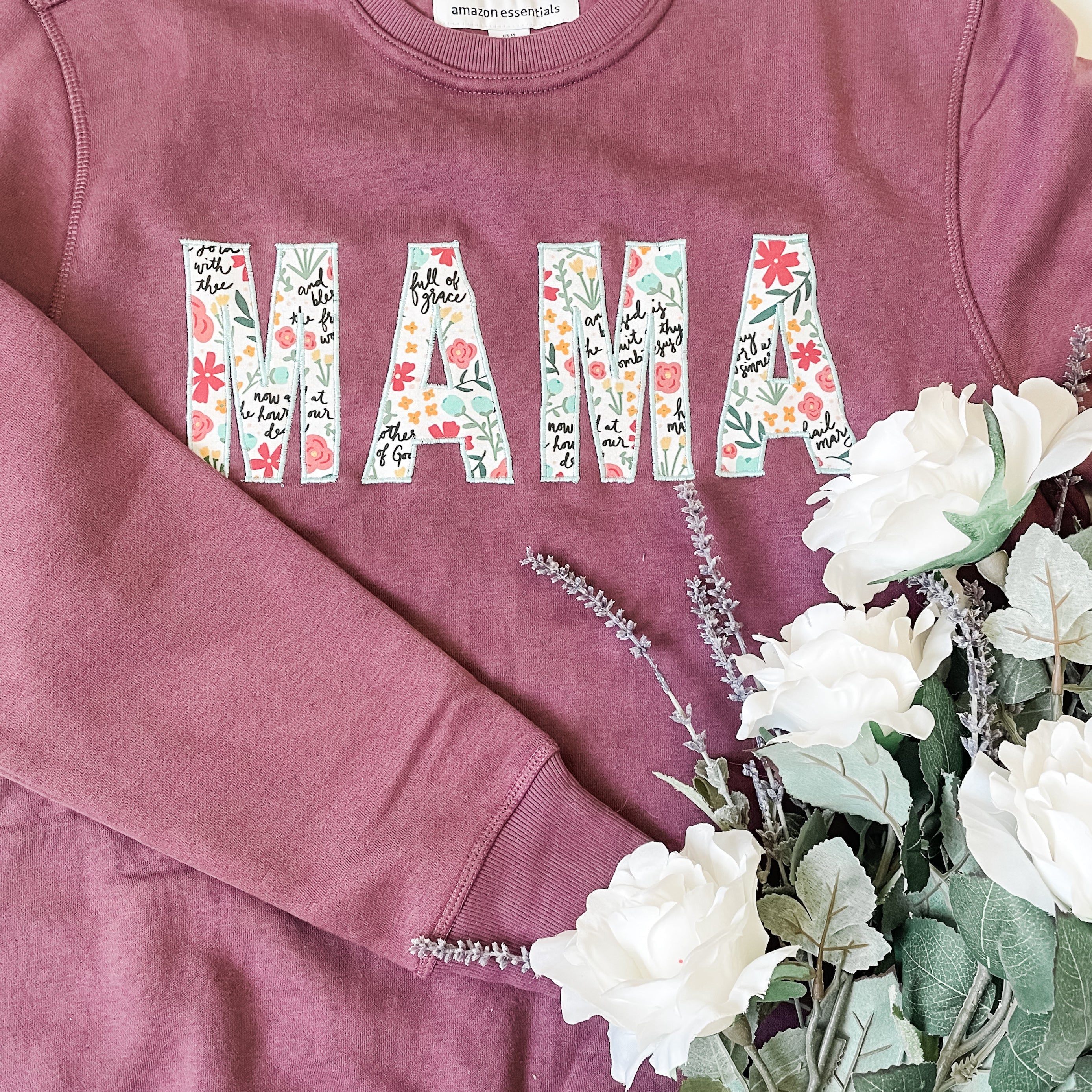 Flat lay of handmade “Mama” embroidered sweatshirt made with Catholic Hail Mary Floral fabric — a modern faith-inspired sewing project for moms.