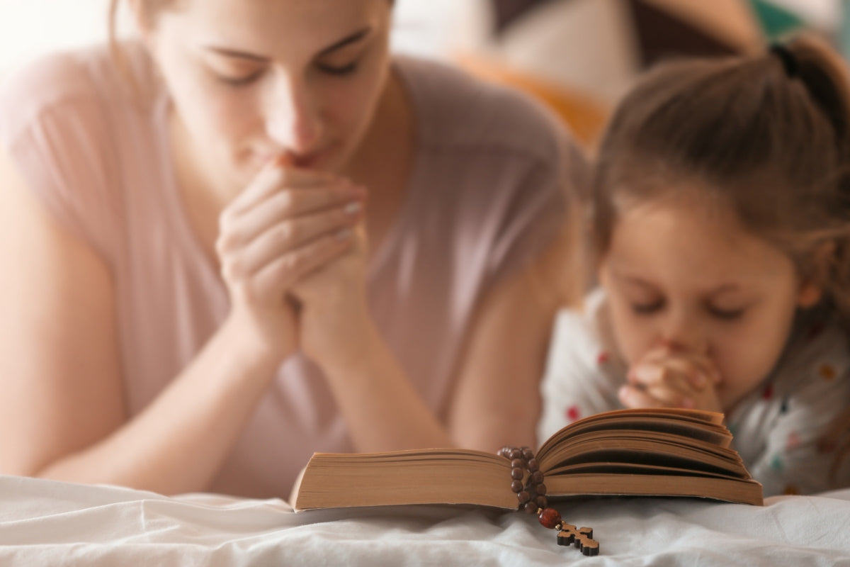 Mother and child praying with Bible and rosary, reflecting on what are the gifts of the Holy Spirit Catholic teaching.