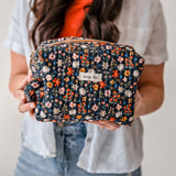 Woman holding a floral patterned cosmetic bag.
