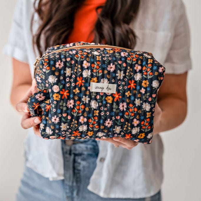 Woman holding a floral patterned cosmetic bag.