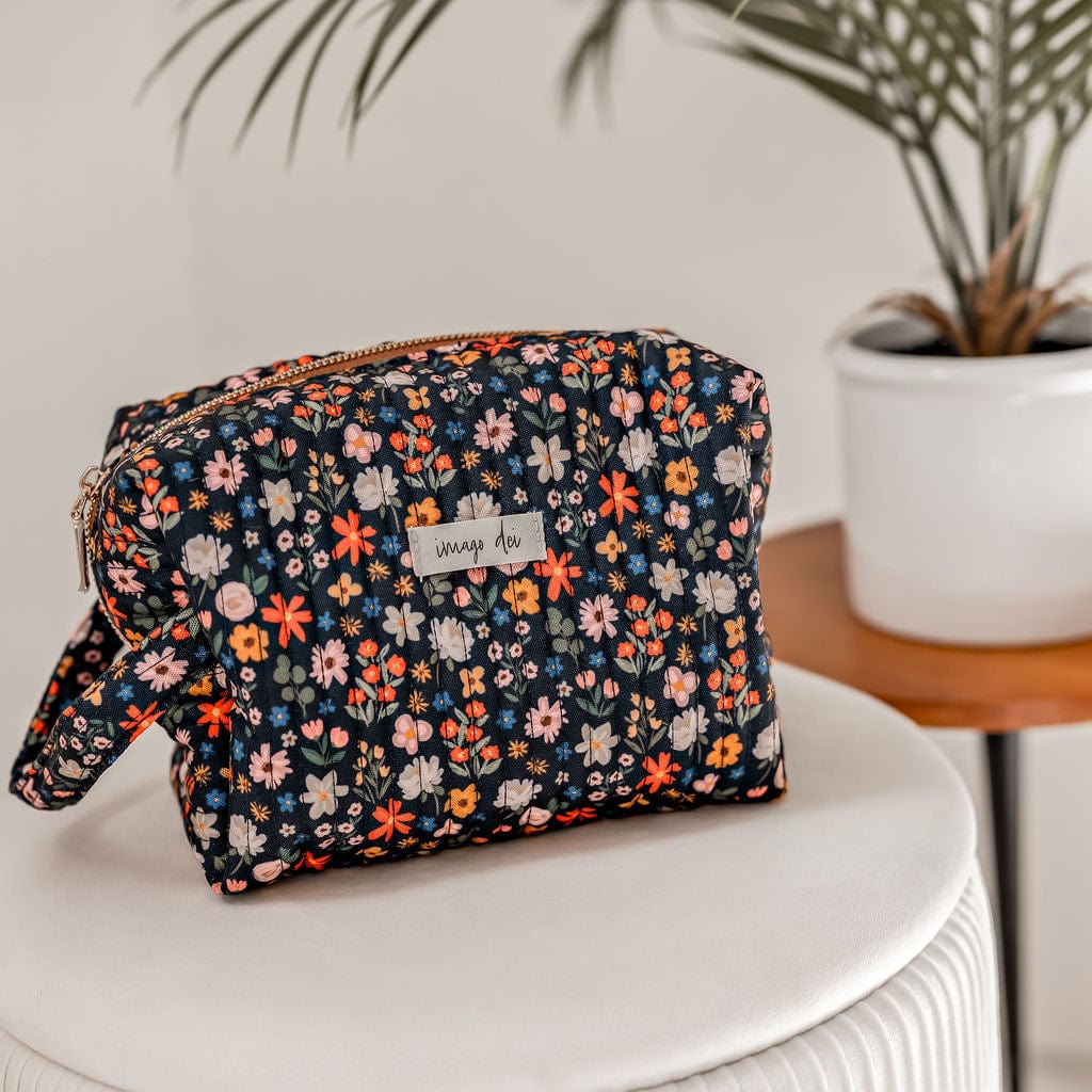 Floral print cosmetic bag on a white stool.
