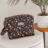 Floral print cosmetic bag on a white stool.
