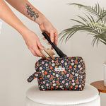Person putting items into a floral makeup bag.