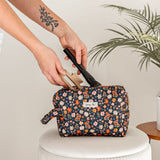 Person putting items into a floral makeup bag.