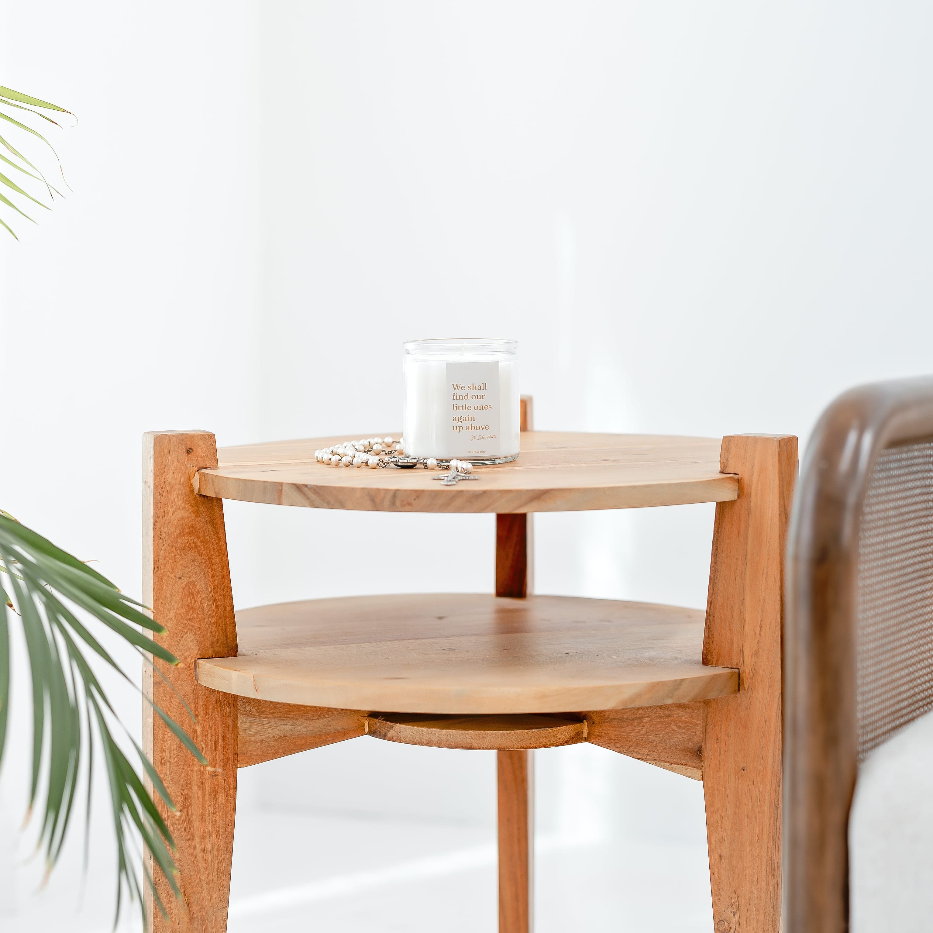 Wooden side table with a candle and plant in a minimalistic room
