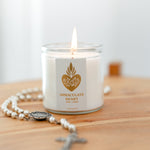 Candle labeled 'Immaculate Heart' with a rosary on a wooden surface