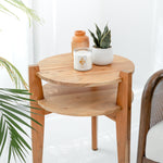 Wooden side table with a candle, vase, and plant on a white background
