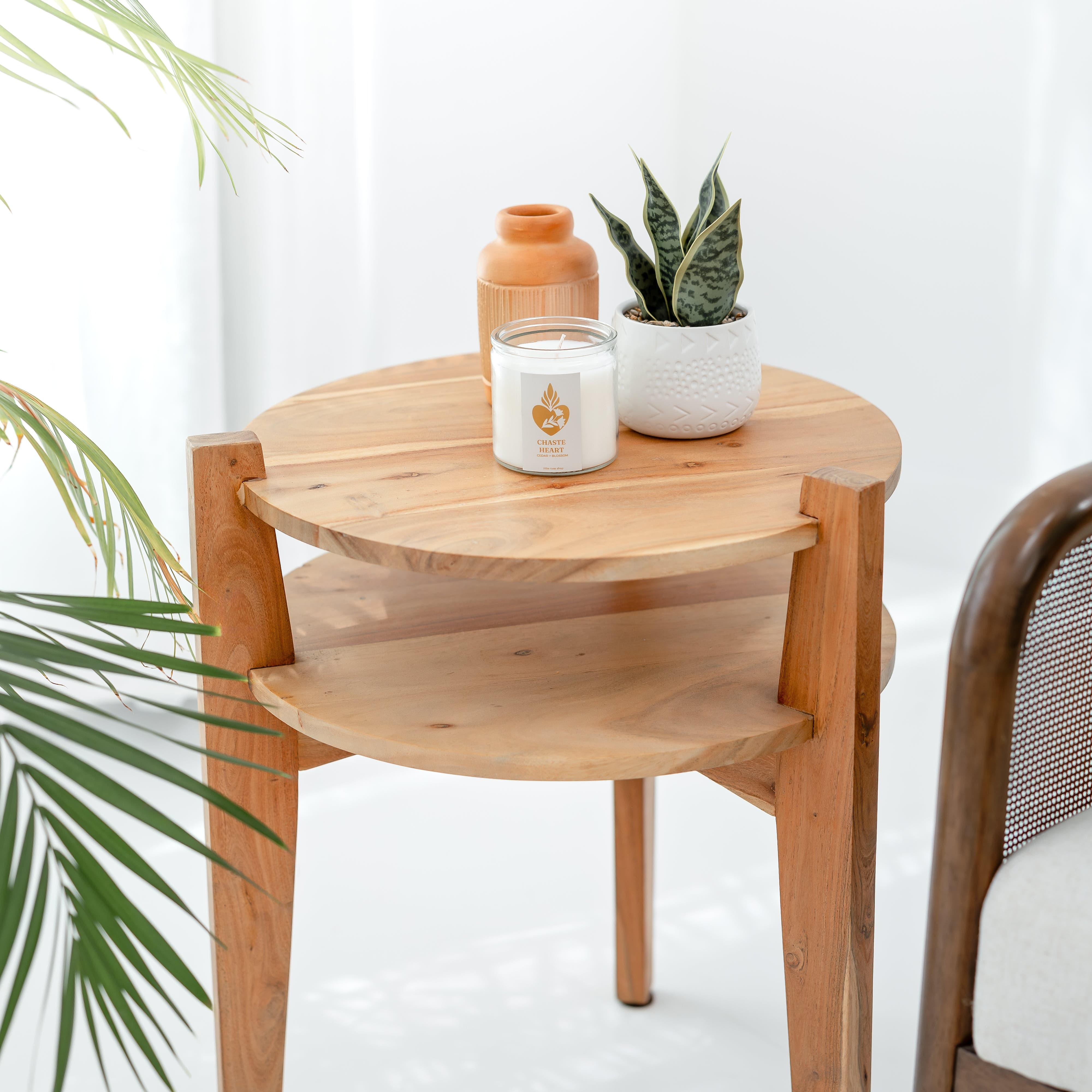 Wooden side table with a candle, vase, and plant on a white background