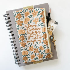 Notebook with pencil, floral pouch, and rosary.