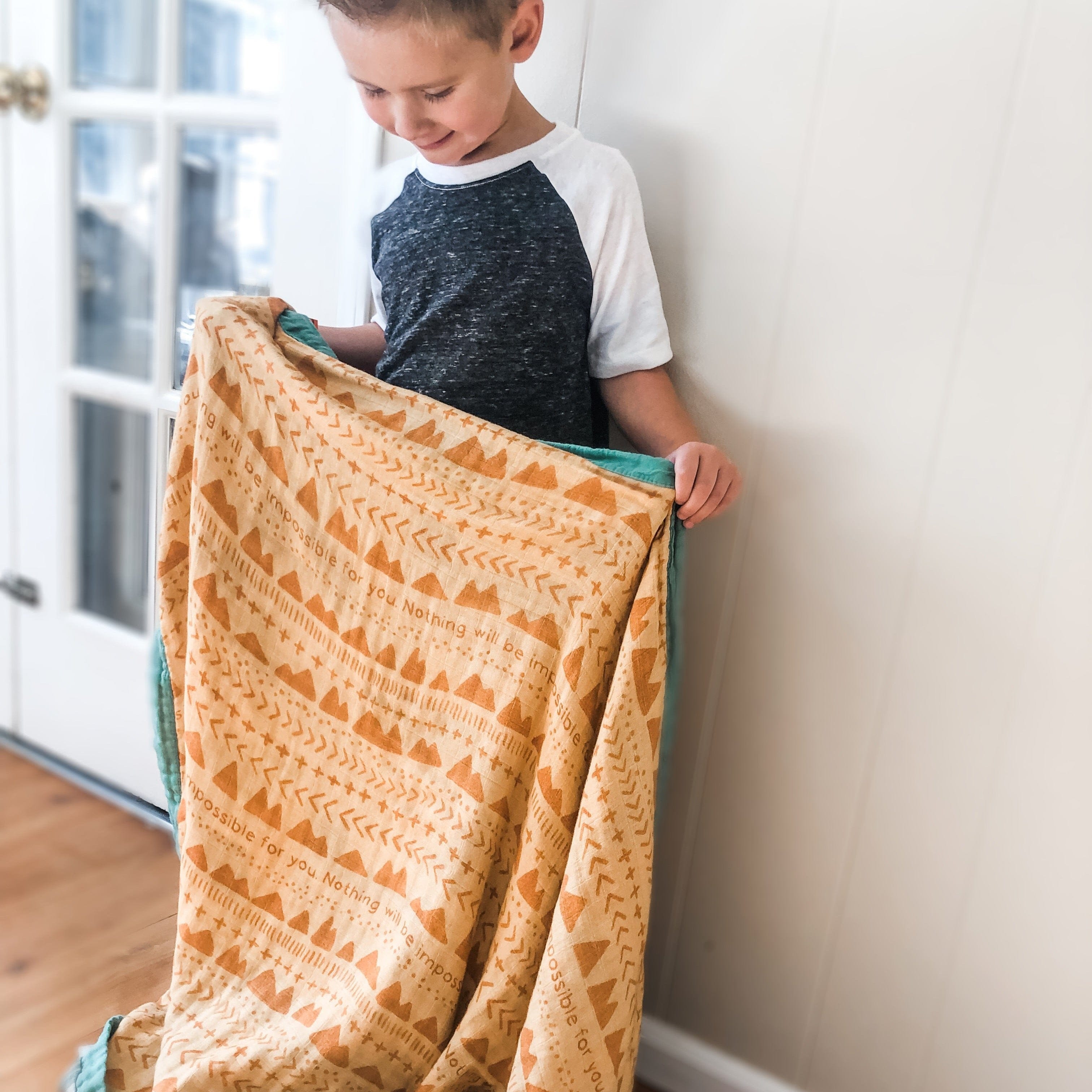 Boy holding blanket with geometric pattern