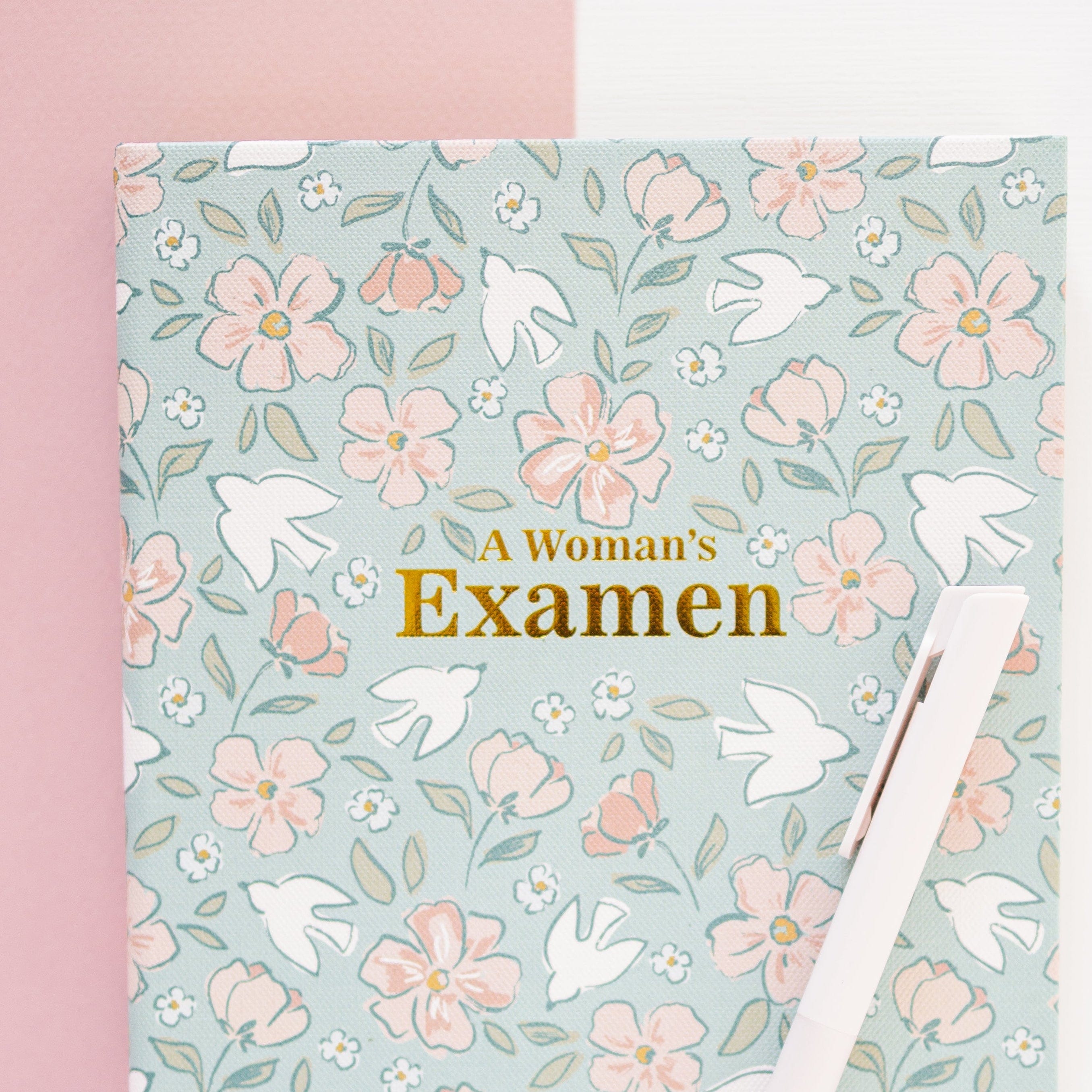 Floral notebook titled 'A Woman's Examen' on a pink and white background