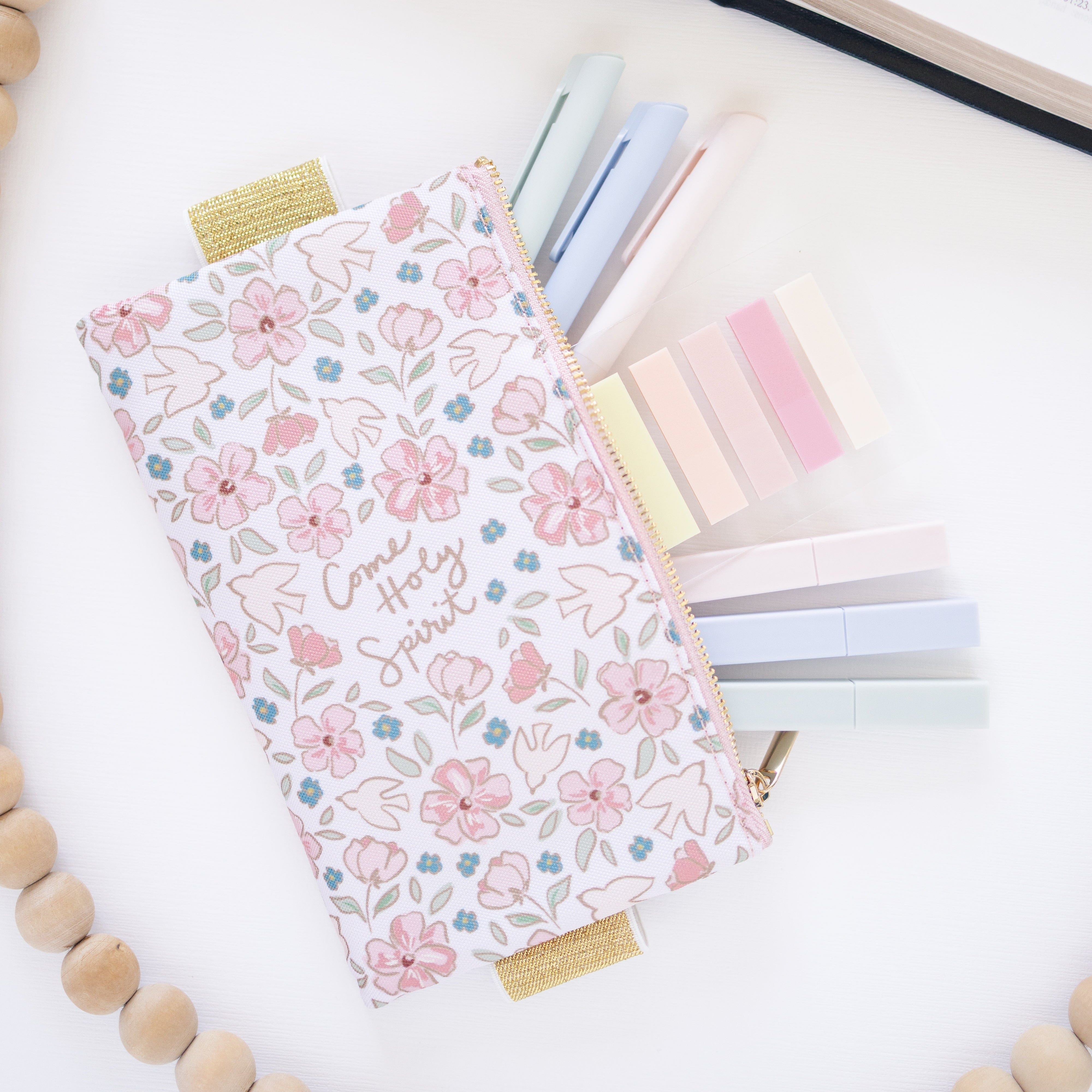 Floral pencil case with stationery items on a white surface