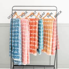 Blankets hanging on a rack, labeled with color names.