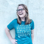 Smiling woman in glasses and teal shirt.