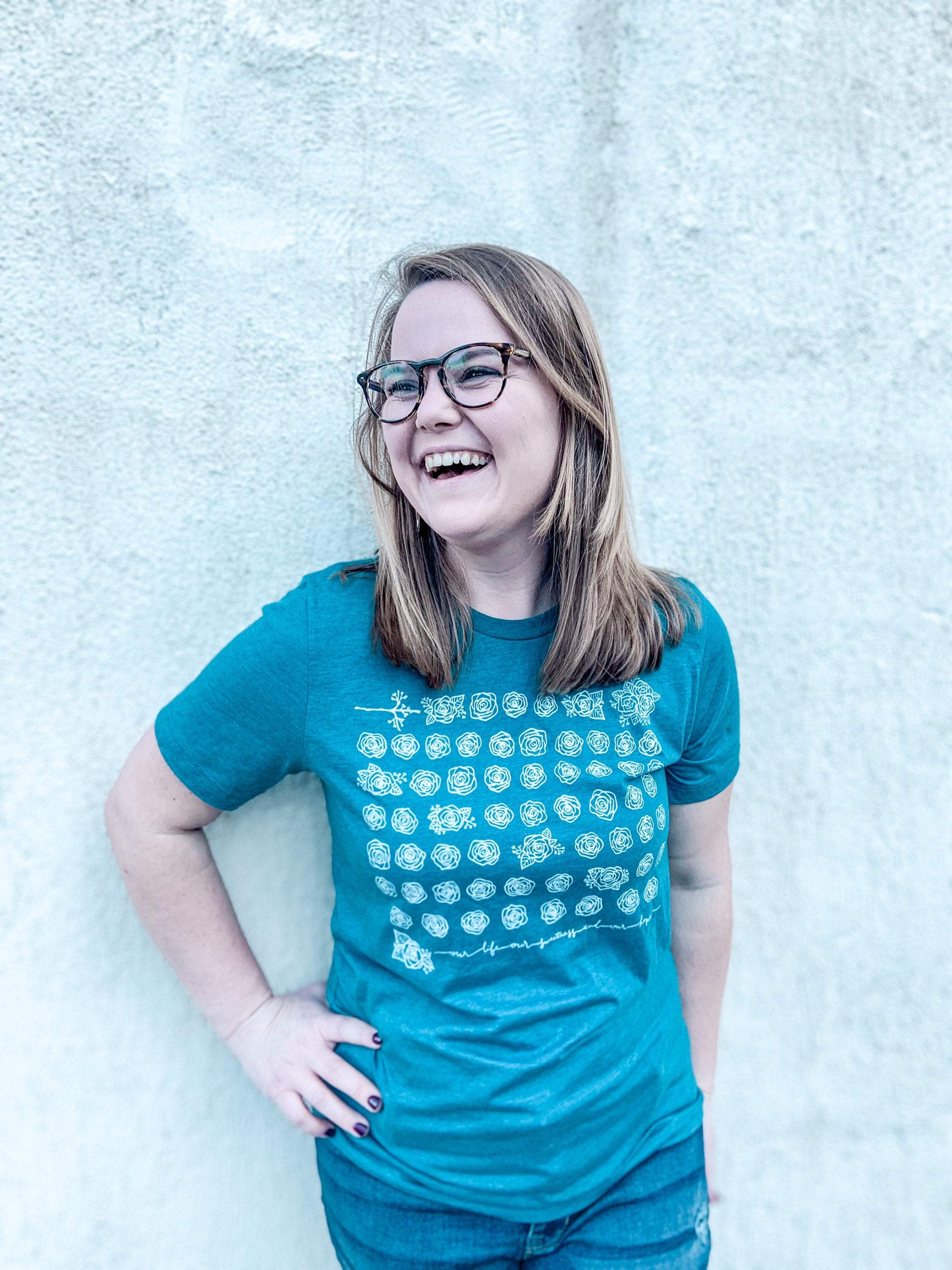Smiling woman in glasses and teal shirt.
