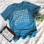 Blue t-shirt with white graphic on a patterned surface.