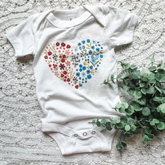White baby onesie with floral heart design.