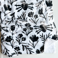 White blanket with black floral pattern.