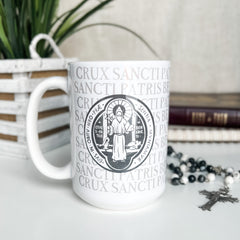 White mug with religious emblem and text.